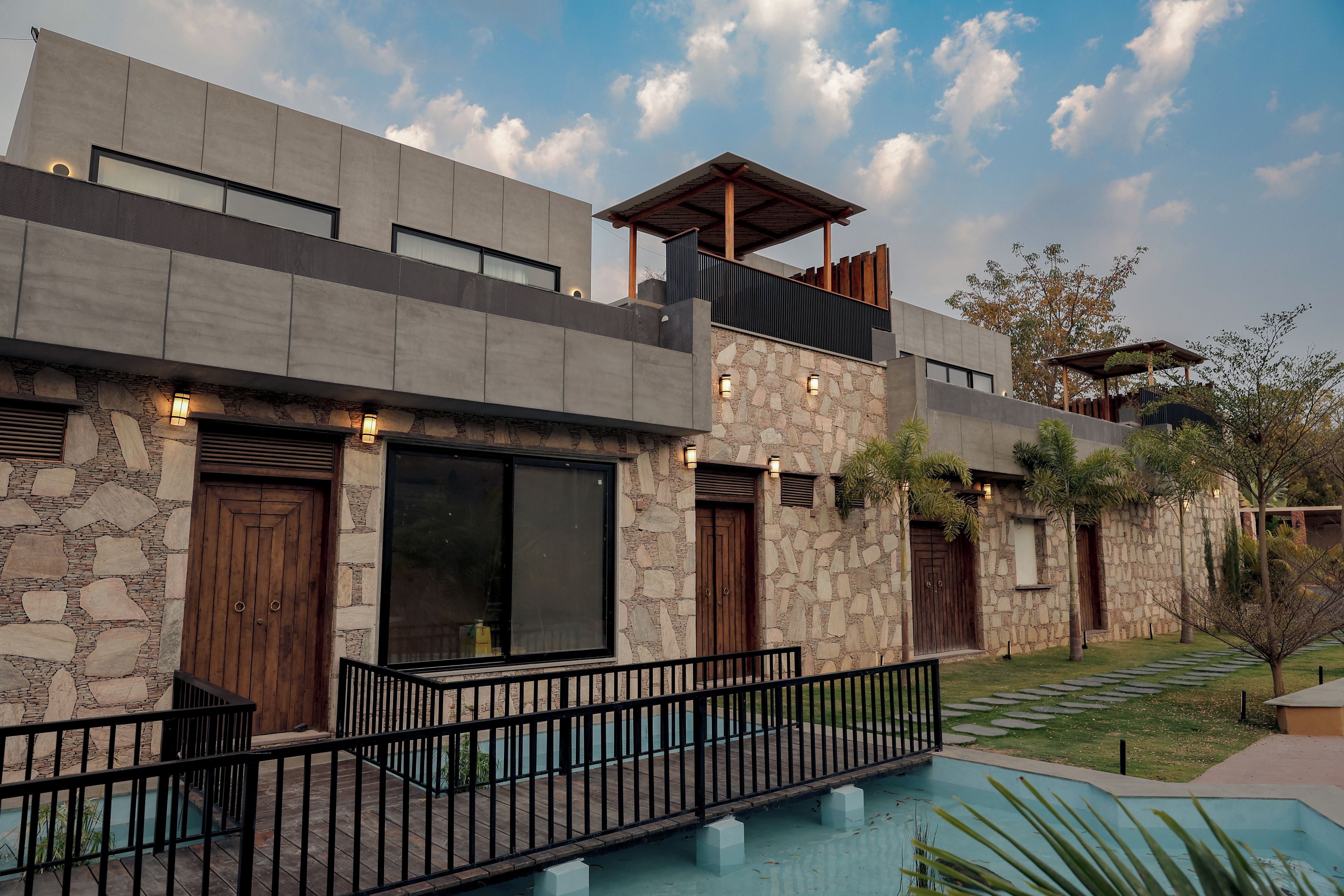 Una casa moderna de dos pisos con fachada de piedra, ventanas grandes y una piscina.