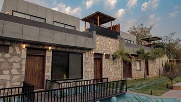 Una casa moderna de dos pisos con fachada de piedra, ventanas grandes y una piscina.