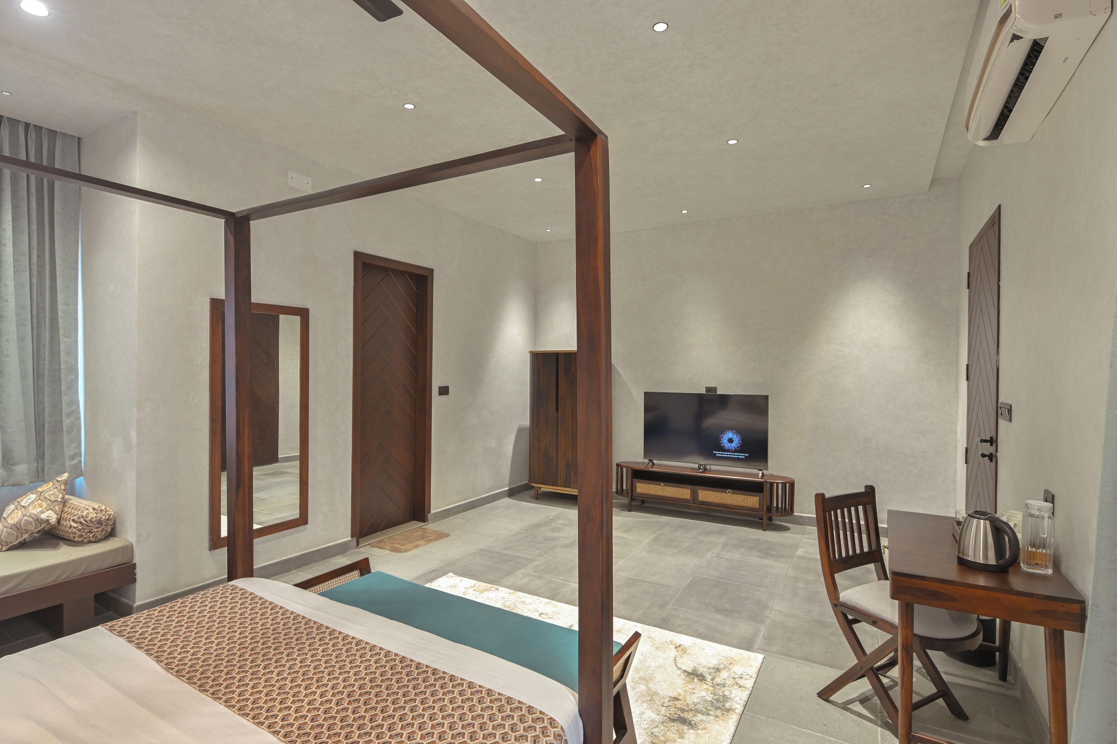 Una habitación de hotel moderna con cama con dosel, televisión, mesa de comedor con una silla y un espejo grande.