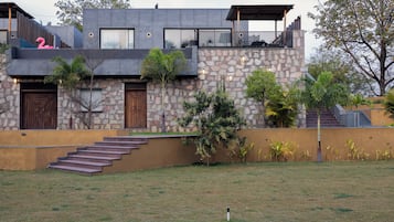 Uma casa moderna de dois andares com fachada de pedra, porta de madeira e varanda com decoração de flamingo rosa.