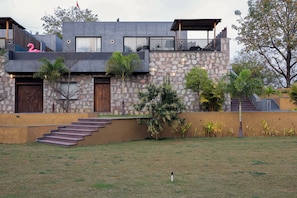 Uma casa moderna de dois andares com fachada de pedra, porta de madeira e varanda com decoração de flamingo rosa.