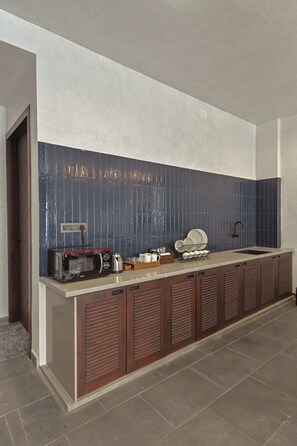 Una cocina moderna con microondas integrado, hervidor y pileta.
