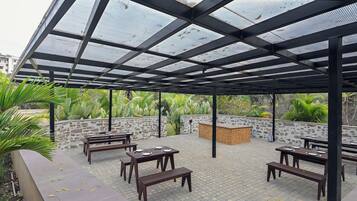 Un patio exterior con techo de vidrio, paredes de piedra y mobiliario de madera.