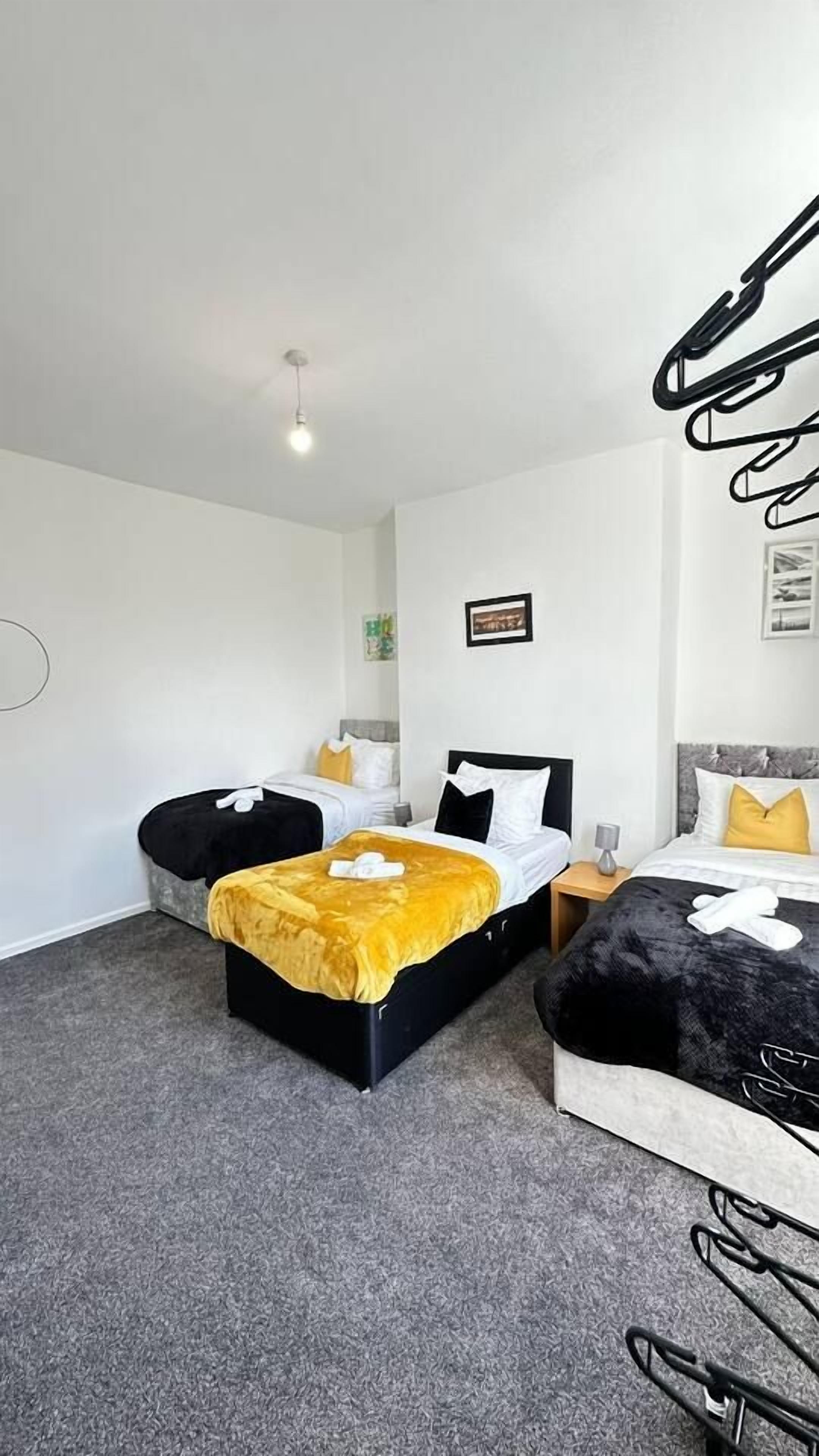 A hotel room with two beds, a grey carpet, and a hanging light fixture.
