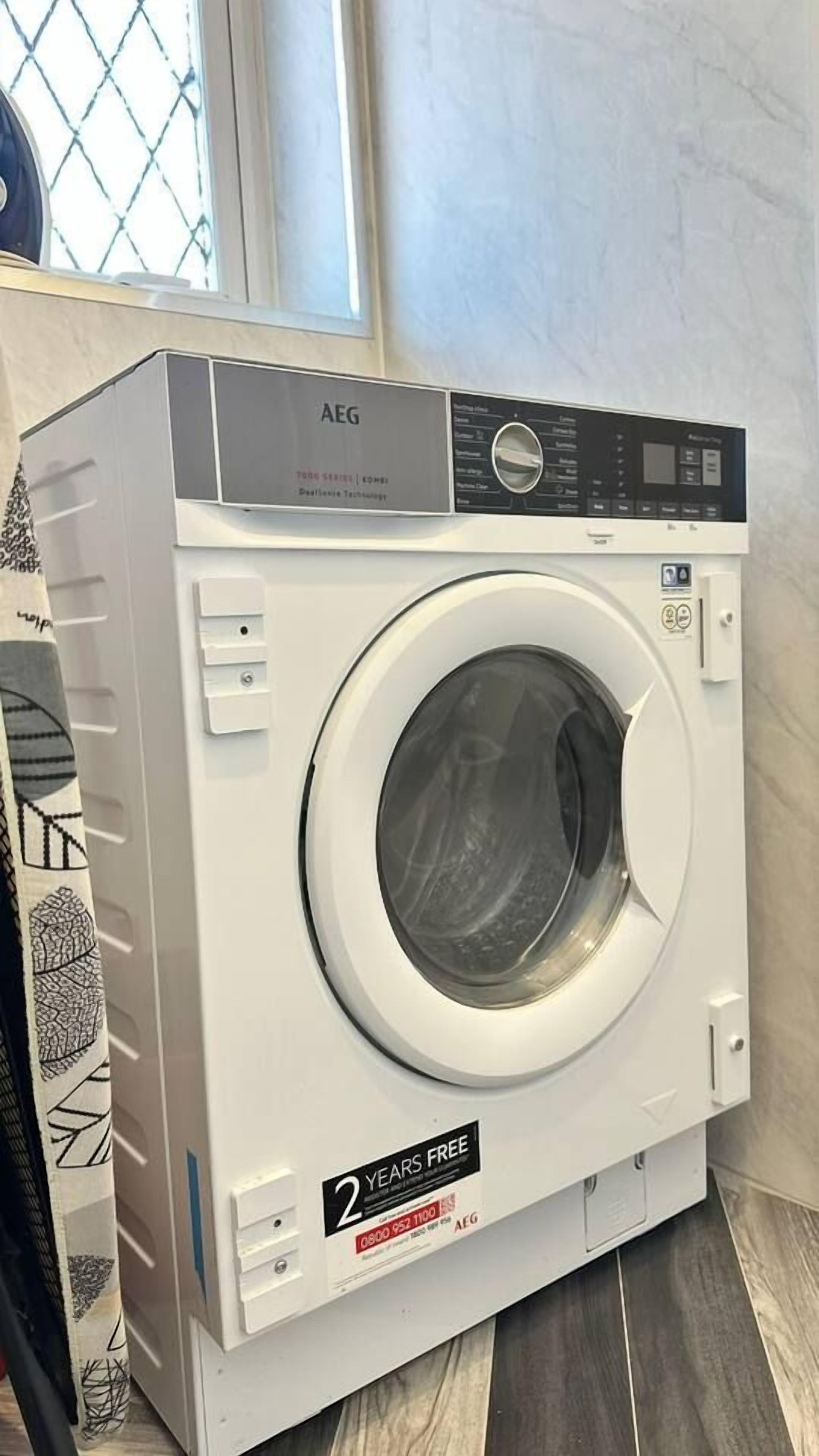 Una lavadora de carga frontal con panel de control digital, un adhesivo que ofrece 2 años gratis y una ventana en la parte superior.