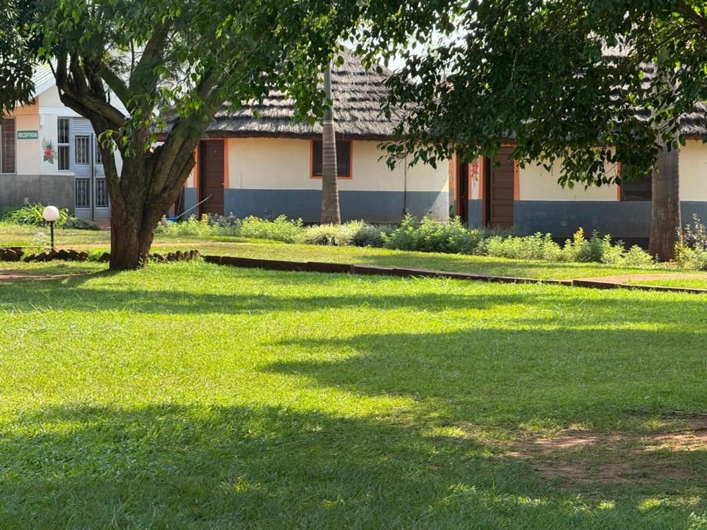 A building with a reception area, a tree in the foreground, and a well-maintained lawn.