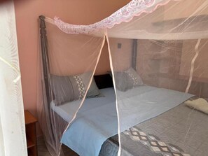 Una cama con mosquitero, almohadas y una colcha estampada.
