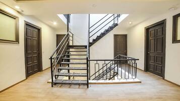 A multi-level interior with a central staircase, plain walls, and doors numbered 205 and 202.
