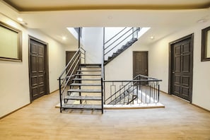 A multi-level interior with a central staircase, plain walls, and doors numbered 205 and 202. - Townhouse Sector 46 Gurgaon Near (Gurugram)