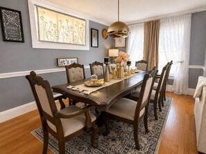 Ein Esszimmer mit Holztisch, sechs Stühlen, einer Chandelierleuchtre und Dekorationselementen.
