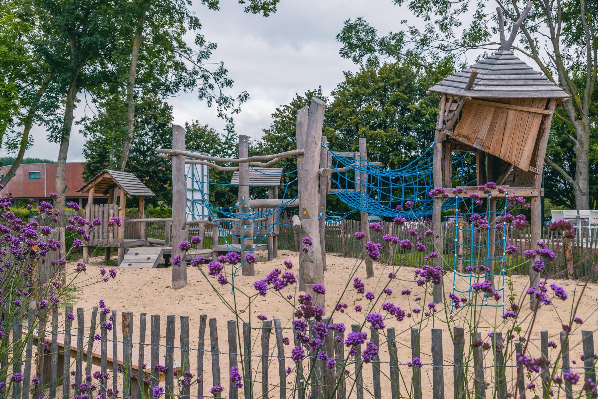 Une aire de jeux avec des structures d’escalade et une cabane en bois.
