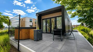 Een modern buitengebied met een zithoek, een houten constructie en een metalen hek.