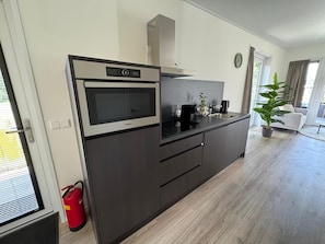 A modern kitchen with a built-in microwave, a coffee maker, and a sink. - Vacation Park Aan de Maas - Weide Lande with a hot tub (Kerkdriel)