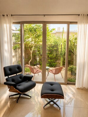 Ein Zimmer mit einer Schiebetür und Zugang zu einer Terrasse mit Stühlen und einem Tisch.