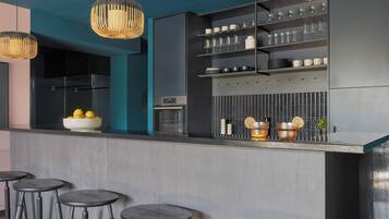 A modern kitchen with a bar area, featuring a built-in oven, a wine rack, and a bowl of lemons on the counter.