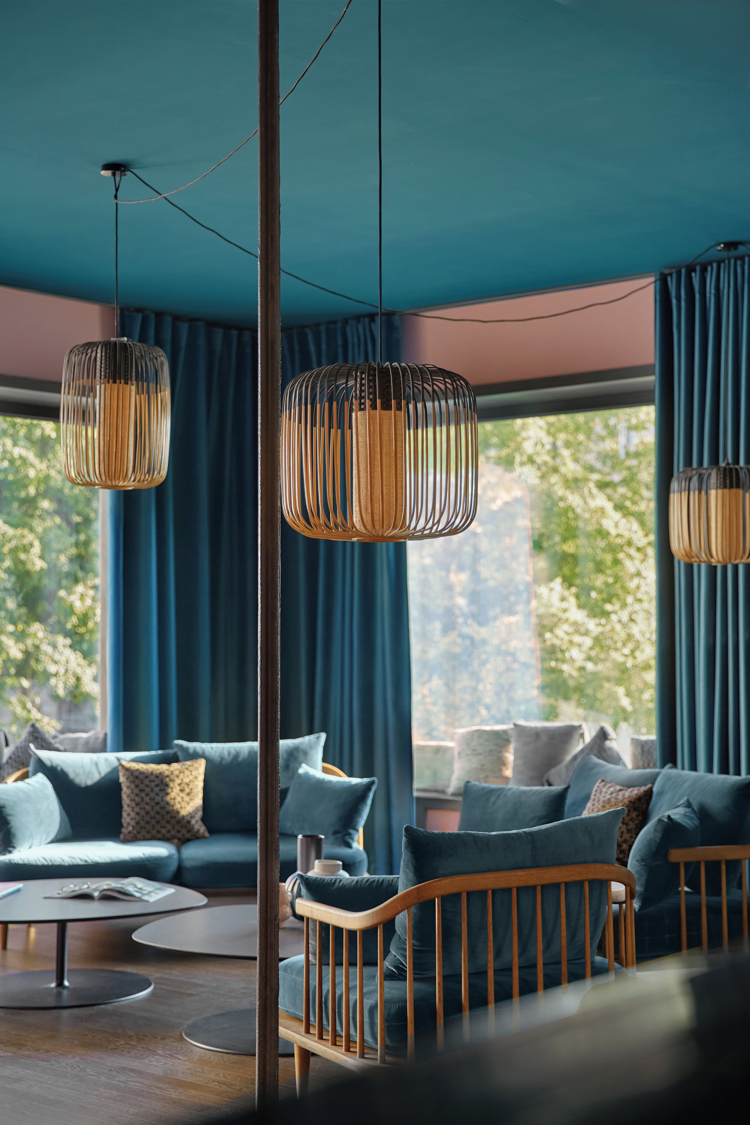 A modern living room with a large window, a sofa set, and hanging pendant lights.