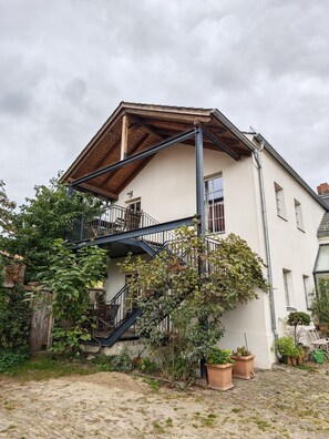 Una casa a due piani con una scala in legno e un balcone.