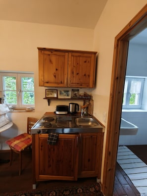 Una cucina compatta con mobili in legno, un forno a microonde integrato e un lavello in acciaio inossidabile.