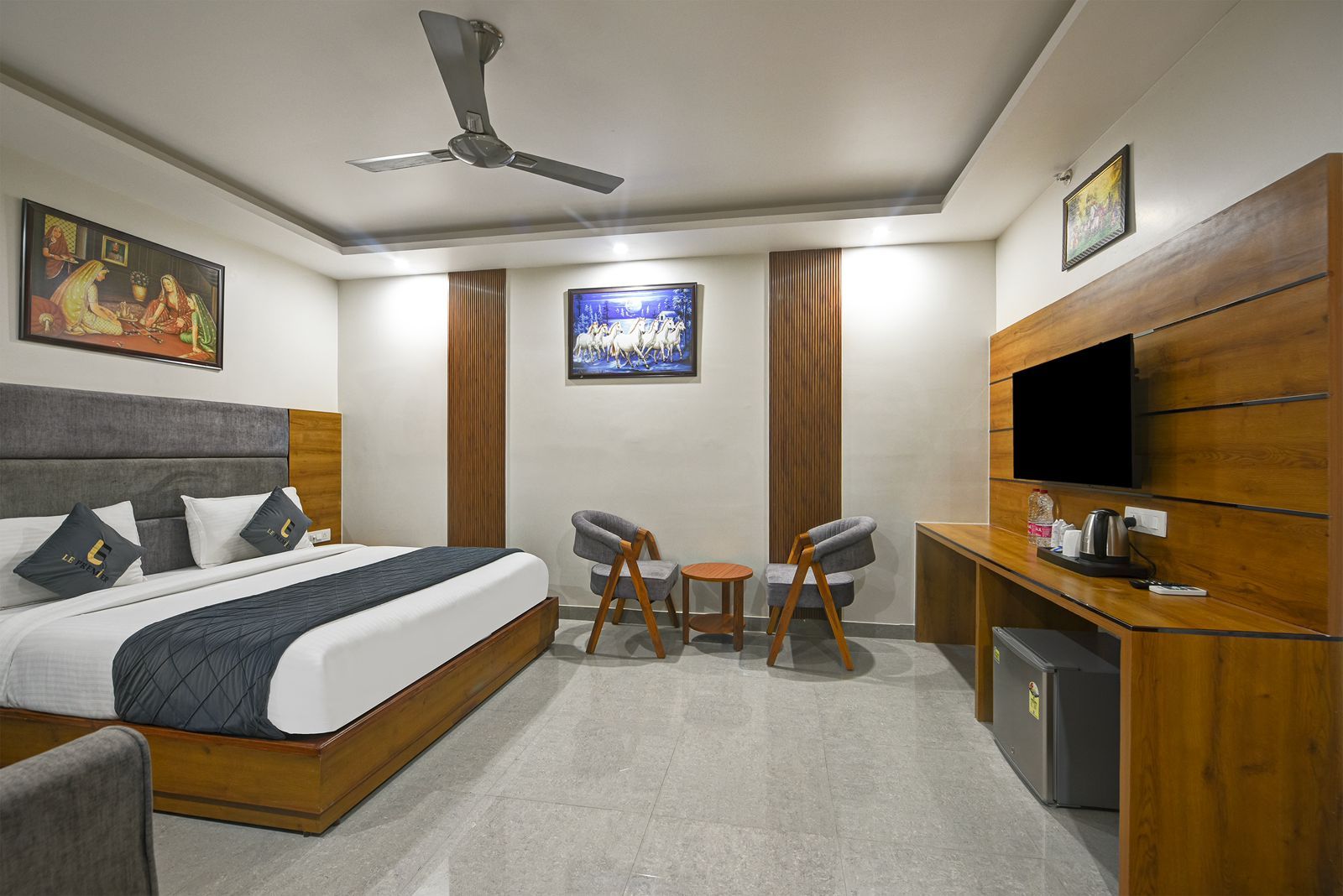 Une chambre d’hôtel avec un lit, un bureau, une télévision et une petite table avec des chaises.