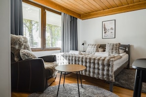 A cozy bedroom with a bed, a chair, a small table, and a window with curtains. - Arctic Pine Studio, Parking By Lapland Host (Rovaniemi)