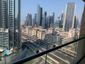 A high-rise building with a view of a cityscape, including several skyscrapers and a busy road below. - Burj View Studio w/ Balcony | Dubai Mall Access (Dubai)