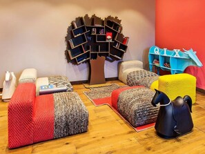 A cozy room with a unique bookshelf, multiple poufs, and a playful black horse-shaped object. - Burj View Studio w/ Balcony | Dubai Mall Access (Dubai)