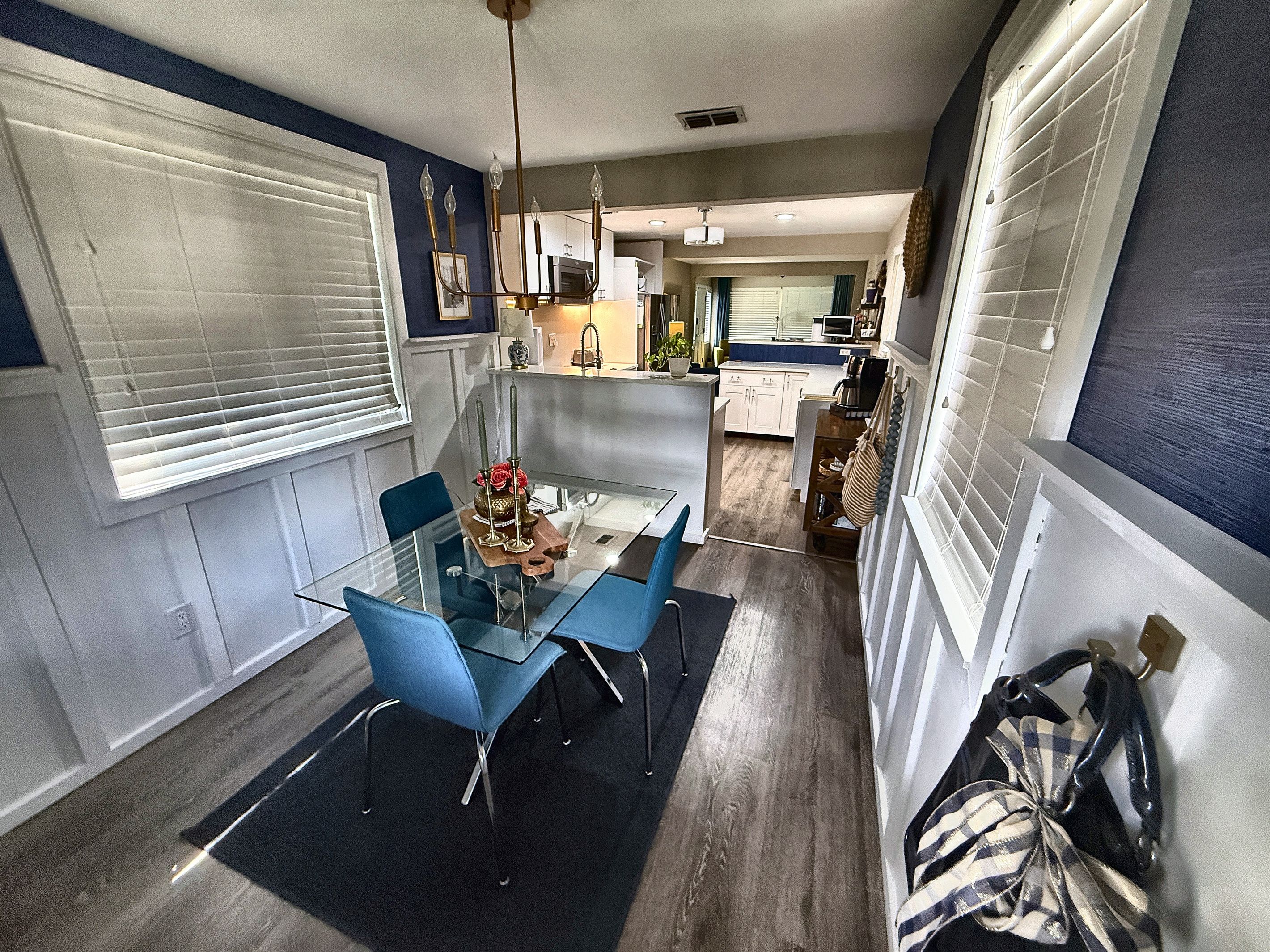Dining area with a glass table and blue chairs, open to the kitchen — great for family meals.