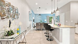 A modern kitchen with a central island, bar stools, and pendant lighting. - Summerville Resort Prime Location Near Disney (Kissimmee)