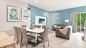 A modern living room with a dining area, a sofa set, and a TV on the wall. - Summerville Resort Prime Location Near Disney (Kissimmee)