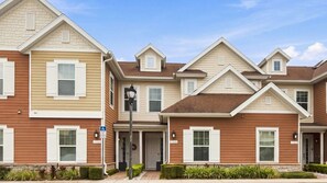 A row of townhouses with a central entrance, a small garden area, and a street lamp. - Summerville Resort Prime Location Near Disney (Kissimmee)
