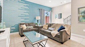 Un salon moderne avec deux canapés, une table basse en verre et un mur d’accent bleu.