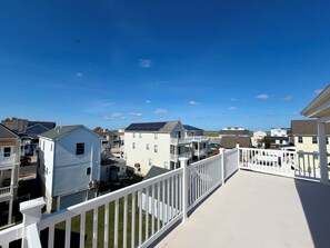 A residential area with multiple two-story houses, a white fence, and a clear blue sky. - Ultimate Family Shore Getaway | 5BR Townhome Sleeps 12 in North Wildwood (North Wildwood)