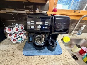 A coffee maker on a kitchen counter with a blue mat, a sink, and a window with a view of the outside. - Ultimate Family Shore Getaway | 5BR Townhome Sleeps 12 in North Wildwood (North Wildwood)