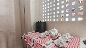 Ein Zimmer mit kariertem Tischlein, einer Kaffeemaschine und einem Teekännchen auf einem Tisch.