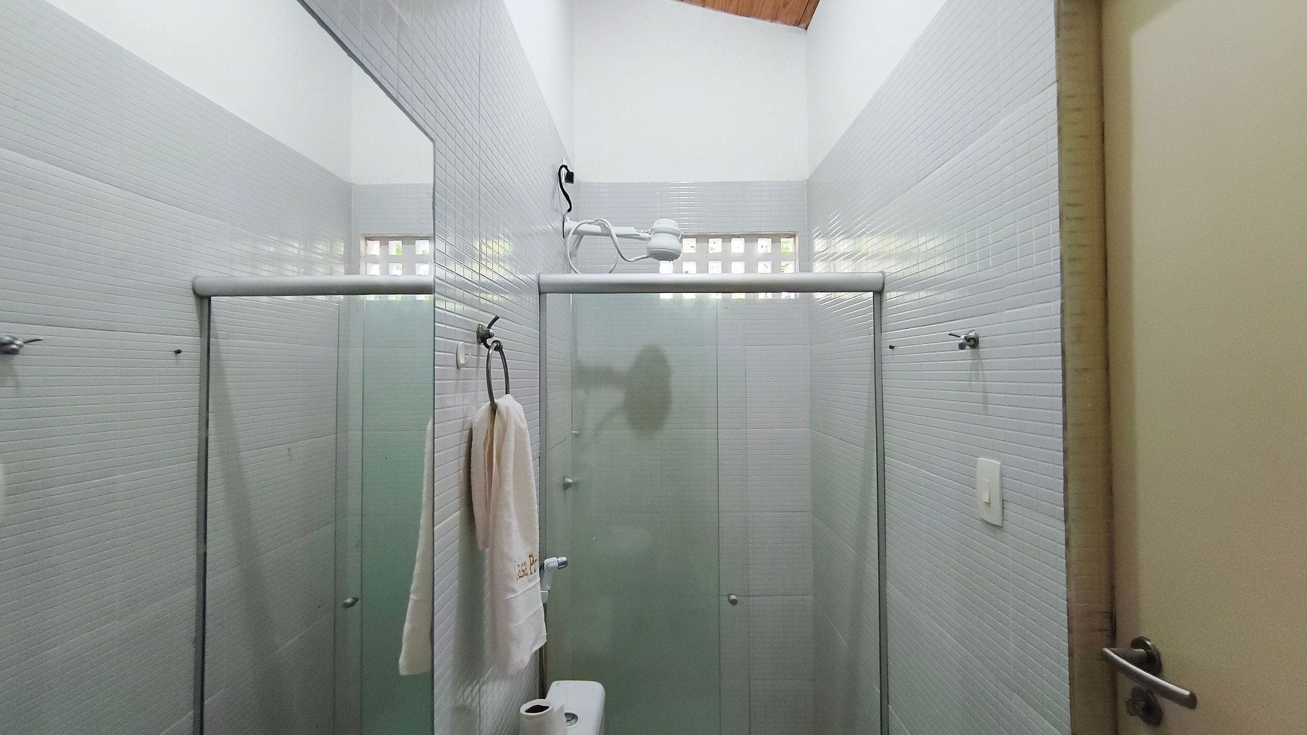 Ein Badezimmer mit einer Duschkabine aus Glas, einem Handtuch auf einem Halter und einer Toilette.