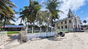 Zona costera con una iglesia, palmeras y una propiedad cercada.