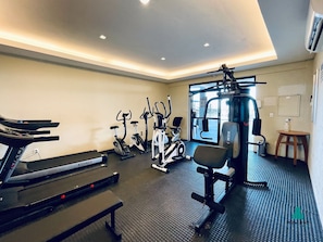 Ein Fitnessstudio mit Trainingsgeräten, einer Bank und einem an der Wand montierten Fernseher.