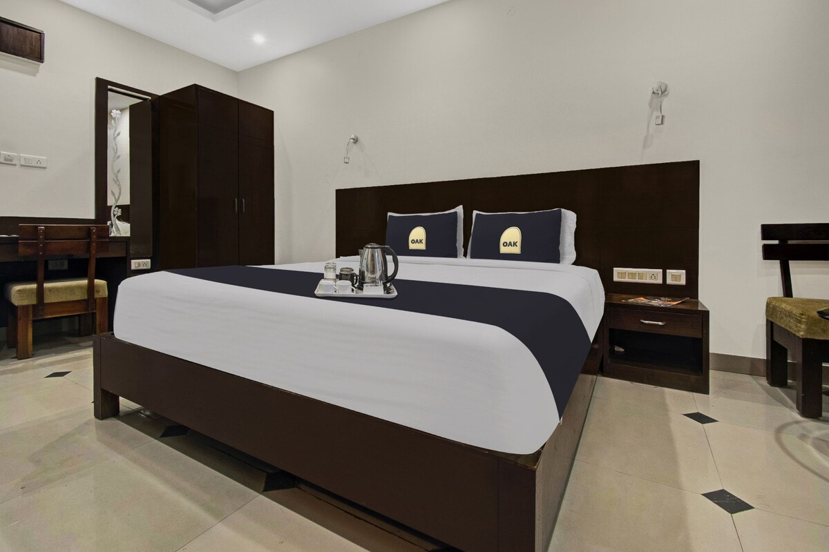 A hotel room with a large bed, a desk, and a wardrobe.