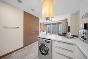 A modern kitchen with a built-in washer, a coffee maker, and a dining area with a view. - Elegant Studio Downtown Dubai (dubai)