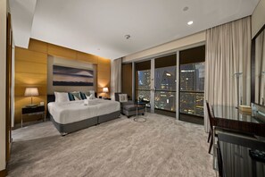 A hotel room with a large bed, a desk, a chair, a city view, and a painting on the wall. - Elegant Studio Downtown Dubai (dubai)