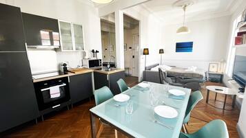 A modern kitchen with a dining area, a sofa, and a TV.