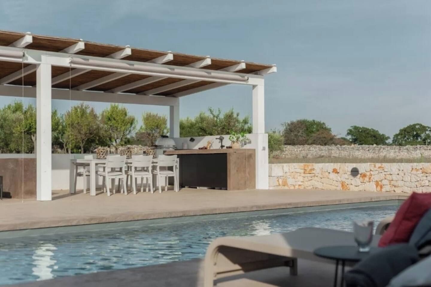 Un espace piscine extérieur doté d’un barbecue couvert et de coins salon.