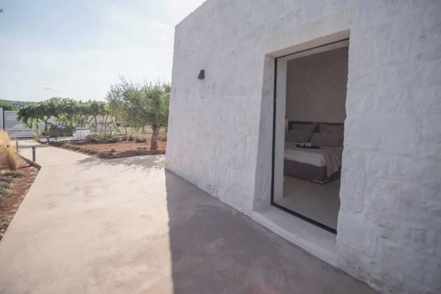 Een modern gebouw met een betonnen pad dat naar een kamer met een bed leidt.