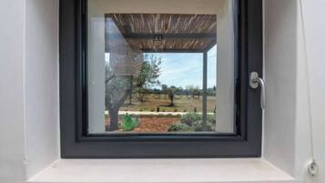 Ein Fenster mit Blick auf eine Außenansicht, darunter ein Baum und eine Wiese.