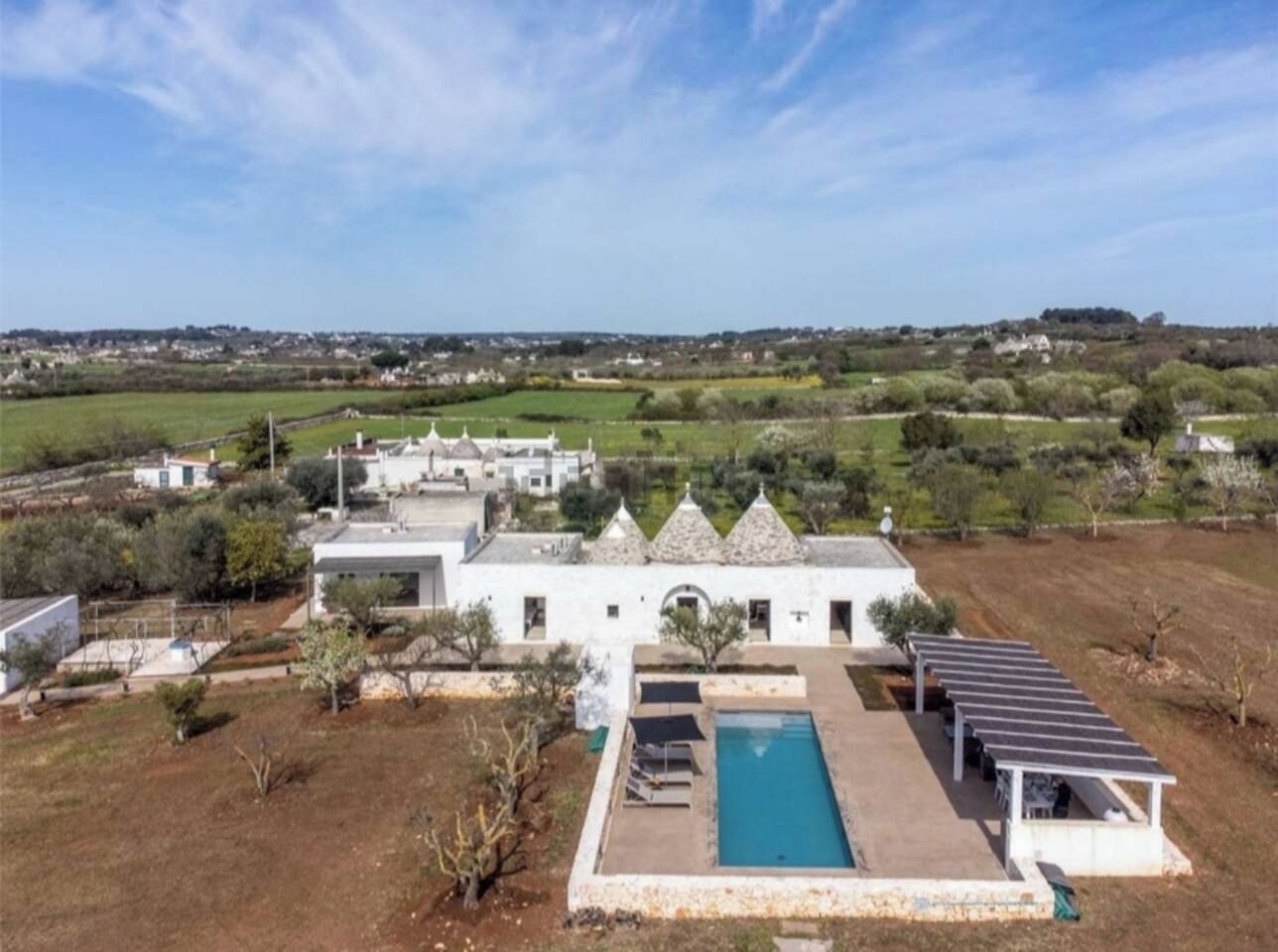 Un grand bâtiment blanc doté d’une piscine et de panneaux solaires.