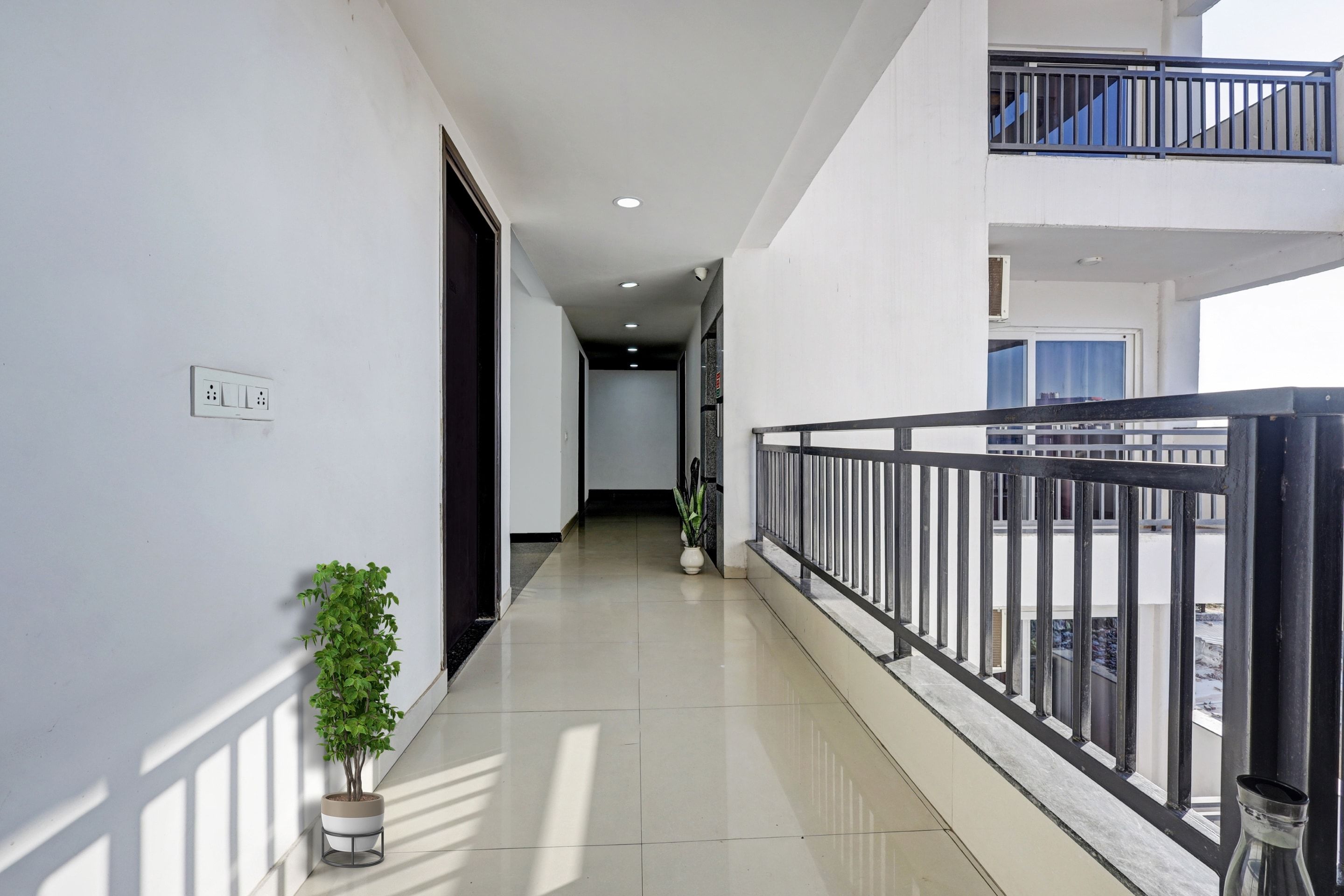 A corridor with a potted plant, a power outlet, and a railing.