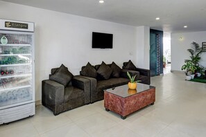 Un área de recepción con un sofá, una mesa de centro, un televisor y una máquina expendedora.