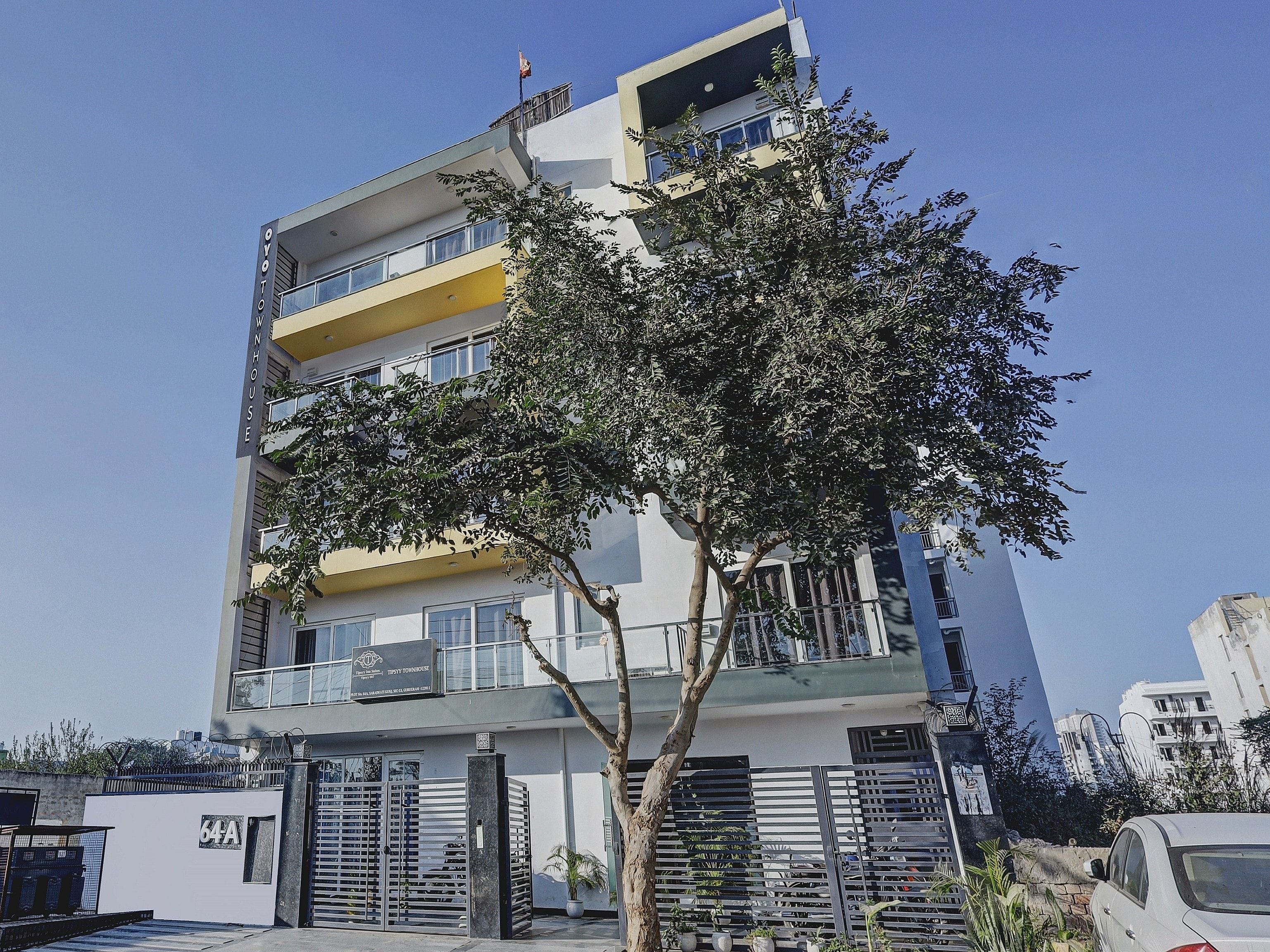 A multi-story building with balconies, a gated entrance, and a clear sky.