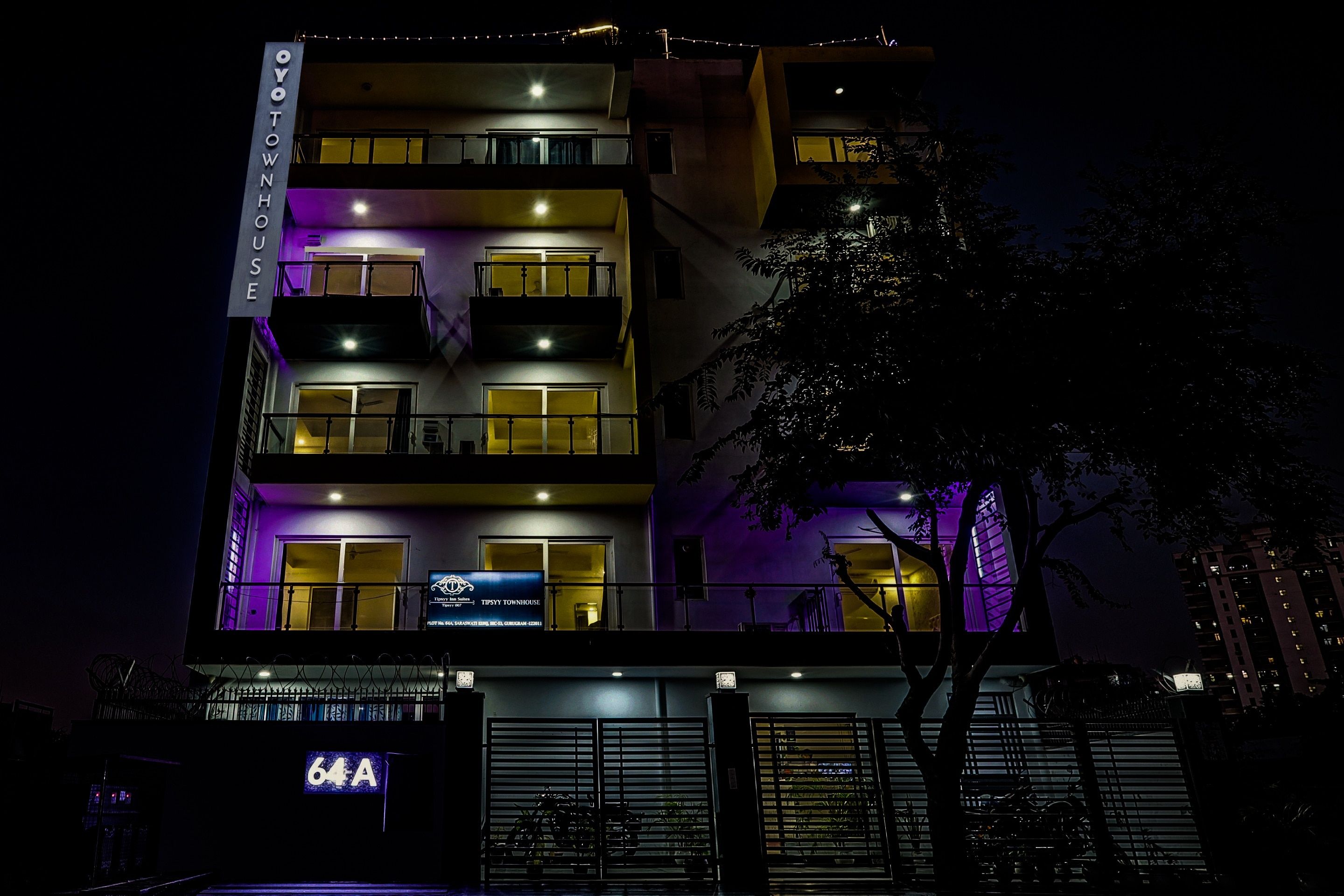 A multi-story building with balconies and a sign indicating 'Tipsy Townhouse.'