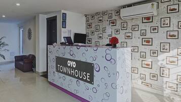 A reception desk with a sign reading 'OYO TOWNHOUSE' and a patterned wall with framed pictures.